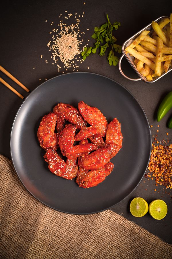 Glazed sesame chicken wings with a basket of fries